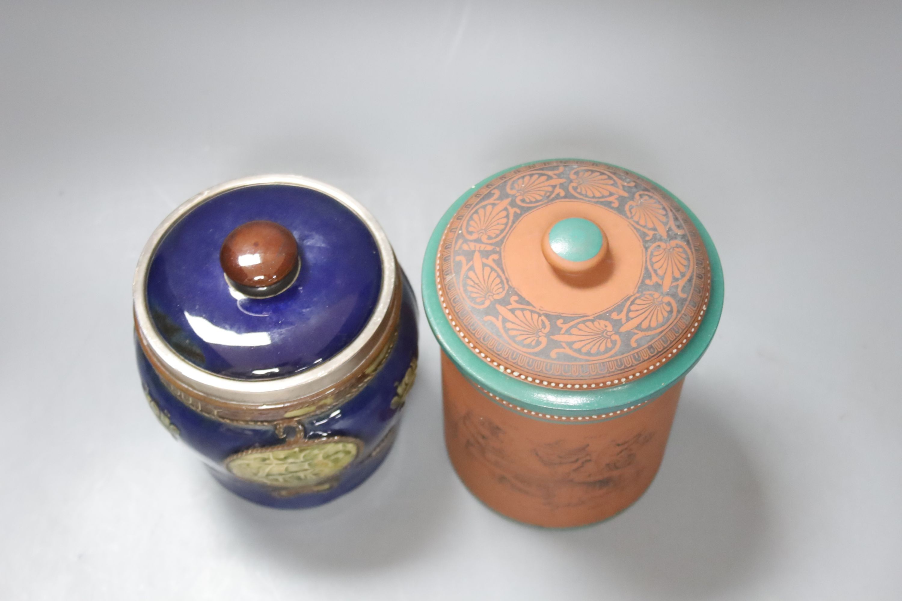 A Doulton Lambeth Nelson commemorative tobacco jar and cover 13.5 cm high, with silver mount (cracked) and a Watcombe style terracotta tobacco jar and cover (2)